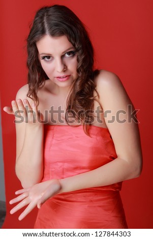 European young woman wearing red dress over bright red background on Beauty and Fashion theme
