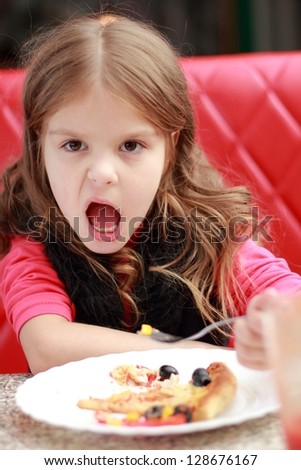 Emotion little girl eating and drinking juice in cafe