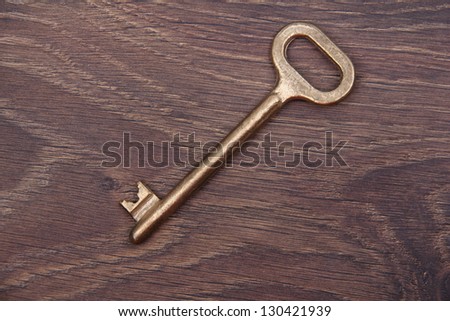 Antique vintage key from a yellow metal on wooden table