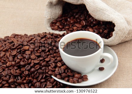 Natural Brazilian coffee beans and a cup of coffee on a light background on Food and Drink