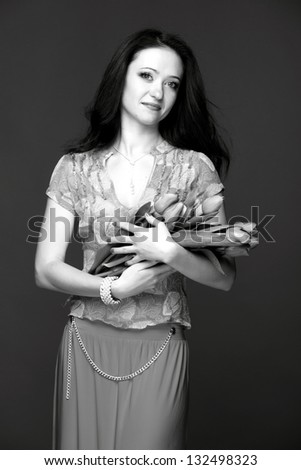 Black and white portrait of a full-length sexy woman with long dark hair and a beautiful smile with tulips on Holiday