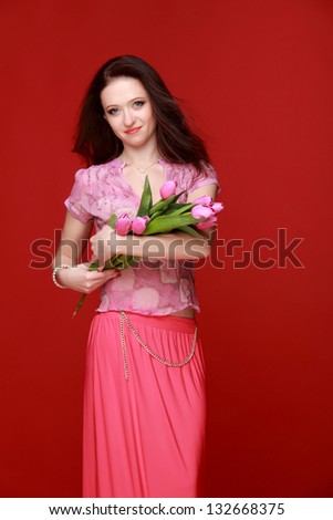 Charming brunette in a pink dress with a beautiful bouquet of tulips