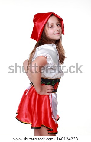 Emotional beautiful little girl dressed as fairy-tale characters in a red hat on a white background on Holiday/Caucasian little girl with a sweet smile in a beautiful dress and red hat