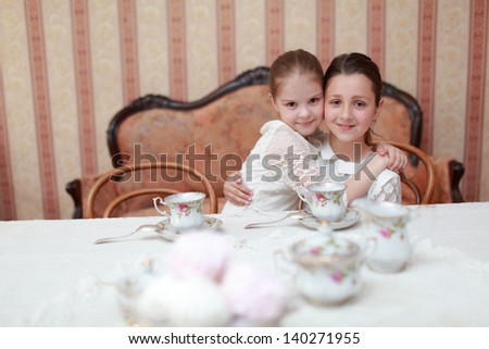Caucasian little girls in white dress sitting at the dinner table and eat breakfast