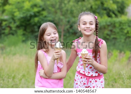 Beautiful little girl in casual clothes eat ice cream on a background of nature in spring