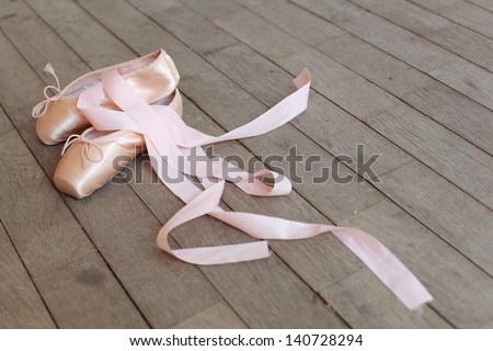 New pair of ballet shoes with ribbons/Baby pink ballet shoes on a wooden floor