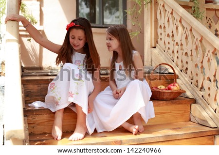 Young girl sitting on the stairs outside the house with bare feet