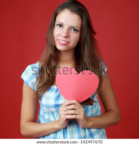 Pretty woman with a heart gift in her hands over red background on Holiday