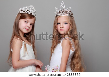 Smiling cute little girls in white dresses and a crown for the beauty contest