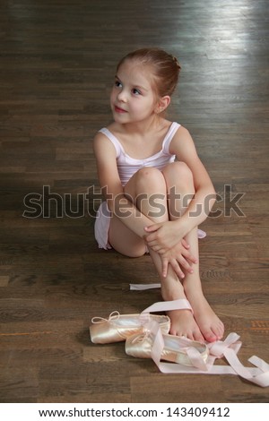Young ballerina puts on pointes in ballet class at the old wooden dance floor