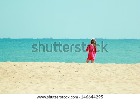 Little girl in bright clothes play and have fun at the sea on a summer theme