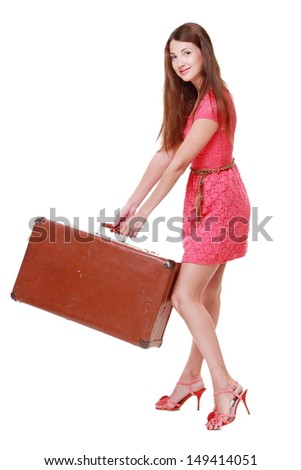 Beautiful young woman lifts a heavy old suitcase isolated on white