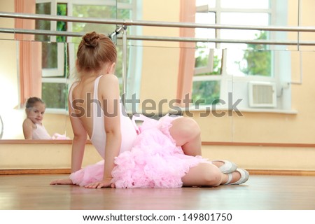 Young girl engaged in a pink ballet tutu and pointes in the ballet hall on the wooden dance floor