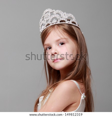 Lovely girl is putting on a diamond diadem on Beauty and Fashion/Young princess smiling and posing for the camera