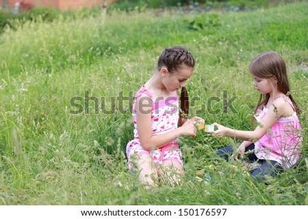Cute little girl sitting in spring grass playing with blocks