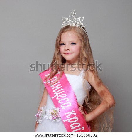 Little girl in princess dress with a red ribbon and the word \