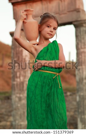 Girl in a bright emerald green dress standing in the ruins of the ancient city of Pantikapaion in the role of the Greek goddess