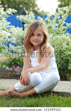 Cute little blond girl in summer clothes outdoors