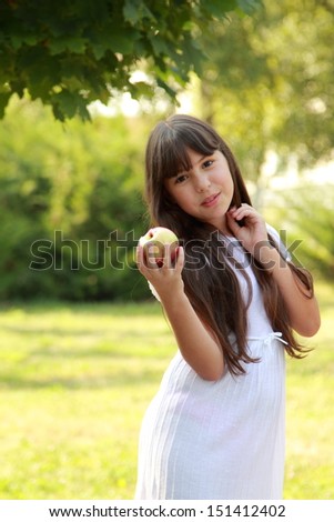Lovely positive girl eats an apple on a picnic in a sunny summer day