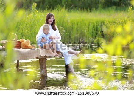 Brunette mom and son blonde enjoying a beautiful summer nature near the lake