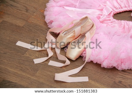 Ballet skirt and ballet shoes for the little ballerina in the background of the old wooden parquet floor