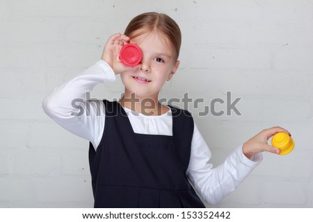 Cheerful little girl in school uniform holding a paint drawing lesson