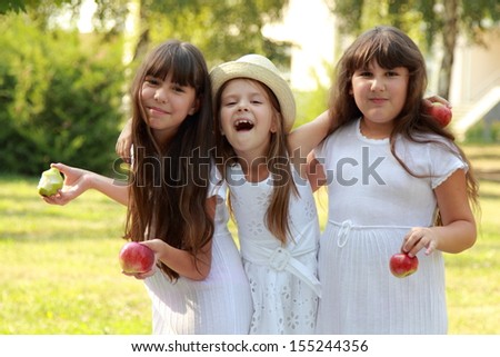 Three happy joyful young girl walking in the park and eat apples