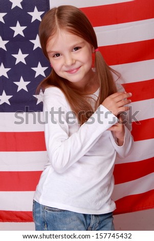 Image of lovely happy smiling little girl on the background of a large U.S. flag/American patriotism