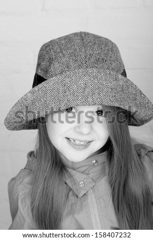 Black and white image of a beautiful smiling little girl in a fashionable hat