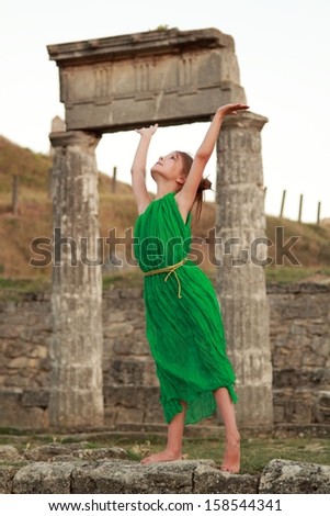 Adorable little girl in the emerald dress on a background of ancient sites of the ancient Greek city of Patikapey/Excavations on Mount Mithridates, the ruins of the ancient city of Pantikapaion, Kerch