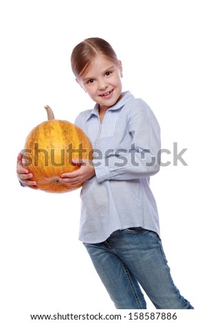 Studio image of a beautiful happy little girl in jeans holding a large orange pumpkin on a white background on Holiday/Little girl with a big pumpkin autumn harvest on Food