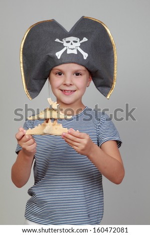 Lovely happy little girl  in the costume of the pirate on gray backgroun
