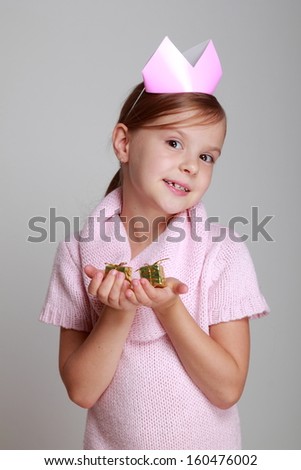 Studio image of a beautiful cheerful little girl in a pink knitted dress