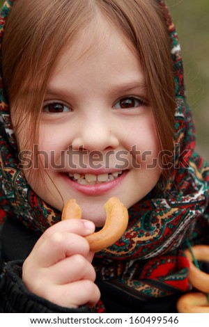 Close up image of beautiful little girl in russian village traditional kerchief with round cracknel with russian ornamen over autumn weather/Lovely russian young girl with traditional russian food