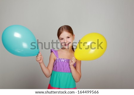 girl with a sweet smile holding a yellow and blue air balloon on Holiday