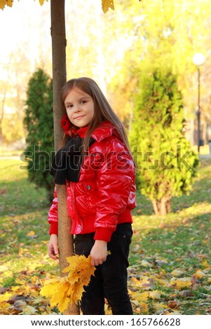 Image of sweet lovely little girl posing on camera over golden leaves at autumn leaves