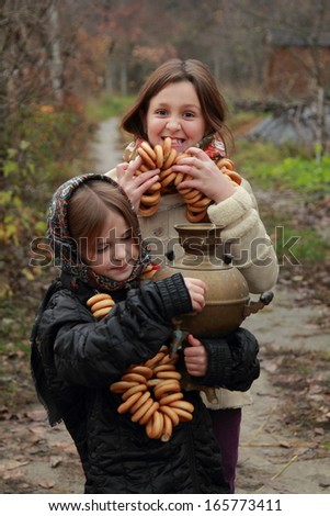 Beautiful little girl in russian village traditional kerchief with round cracknel with russian ornament over autumn weather/Lovely russian young girl with traditional russian food