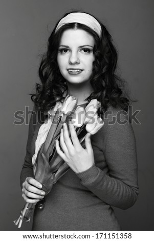 Black and white image of beautiful young woman with fresh tender tulips/European young girl with a bouquet of spring flowers