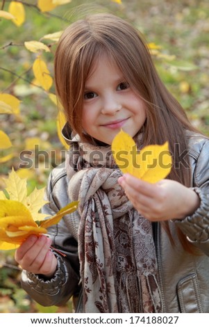 Little girl with lovely smiley holding leaves  at autumn /Funny smiley happy little girl posing on camera