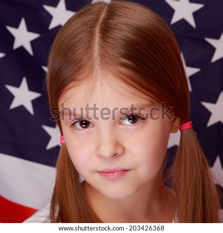 Portrait of cute happy smiling little girl on the background of a large American flag/American Independence Day