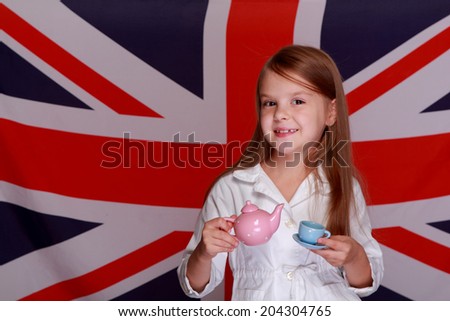 Smiling little English lady drinking tea from a cup of kids on background of the flag of the United Kingdom