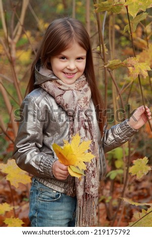 Little girl with lovely smiley holding leaves  at autumn /Funny smiley happy little girl posing on camera