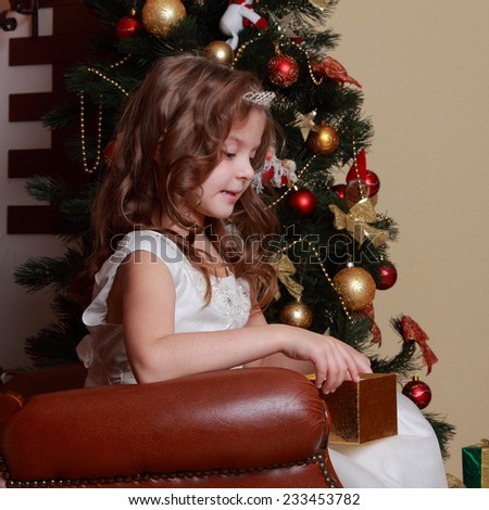 A little girl in a dress of Princess around the Christmas tree on Holiday theme