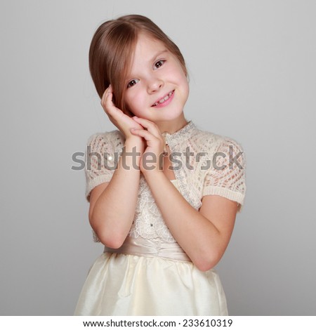 Cute little girl in dress think, dream looking up/Caucasian adorable princess on grey background