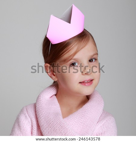 child in a pink knitted dress with a pink crown