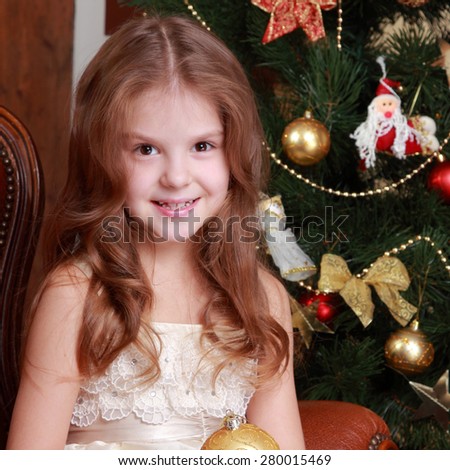 Beautiful young princess holding decorative golden ball for christmas tree on Holiday theme/Gorgeous little lady on Christmas