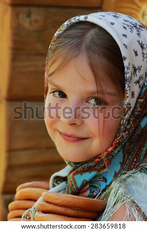 image of beautiful little girl in russian village traditional kerchief with round cracknel with russian ornamen over summer weather