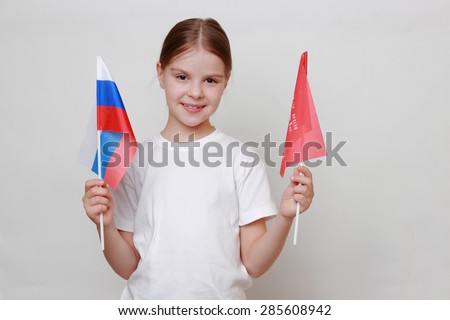 Proud little girl holding national flag of Russian Federation (Russia) and Victory Banner - Assault flag of the 150th Order of Kutuzov II Degree Idritsa Infantry Division in the second World War