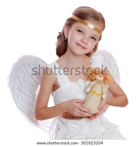 Studio portrait of beautiful little angel holding lovely angel doll and sitting on a cloud isolated over white background on Holiday theme