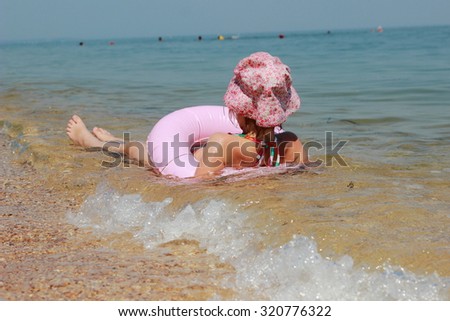 Cute little girl in panama swims in the sea with clean water with a lifeline in a sunny summer day